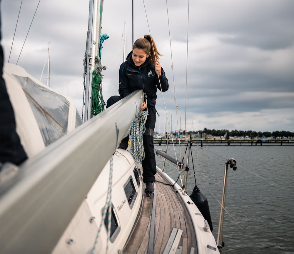 Seglerin an Deck einer Segelyacht im Hafen